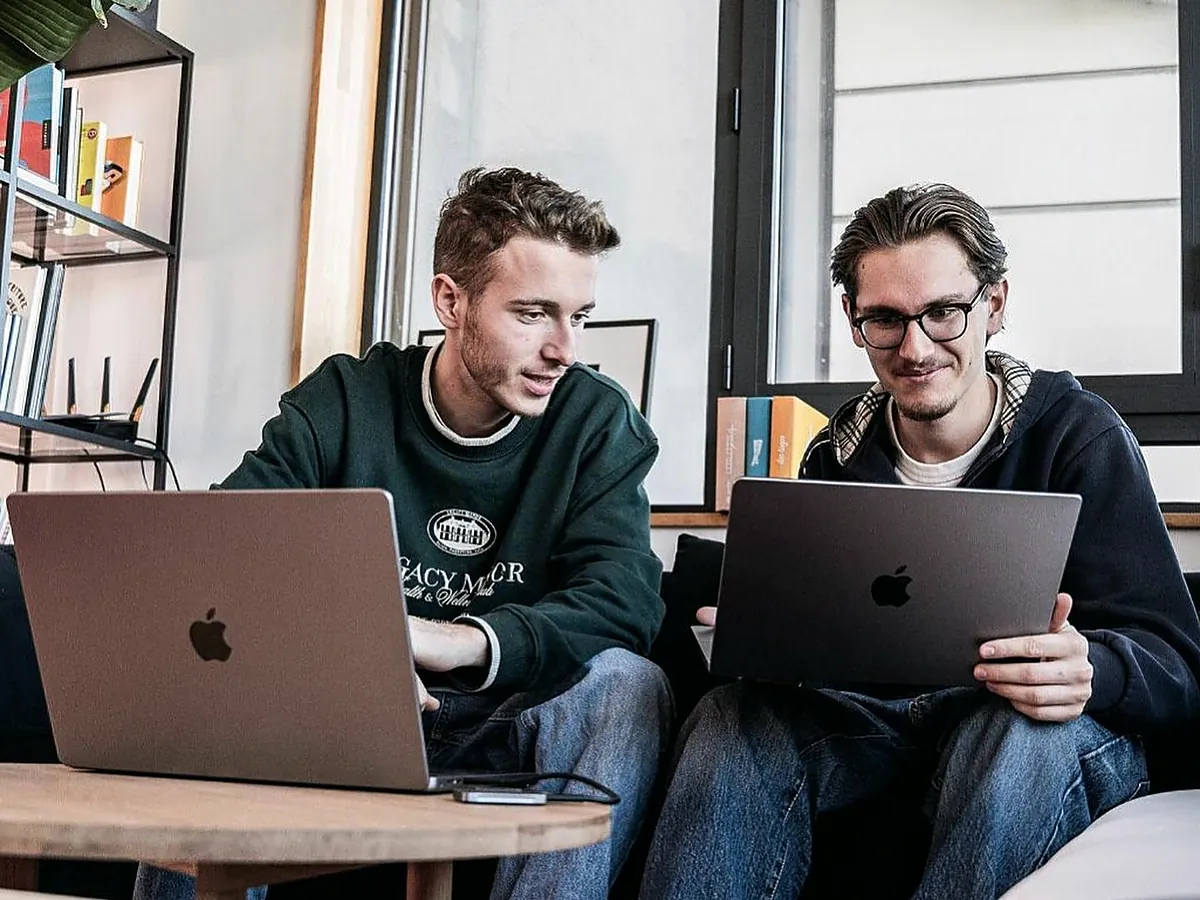 Two colleagues reviewing a financial model on laptops